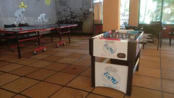 A room with a foosball table, ping pong table, and a table tennis table.