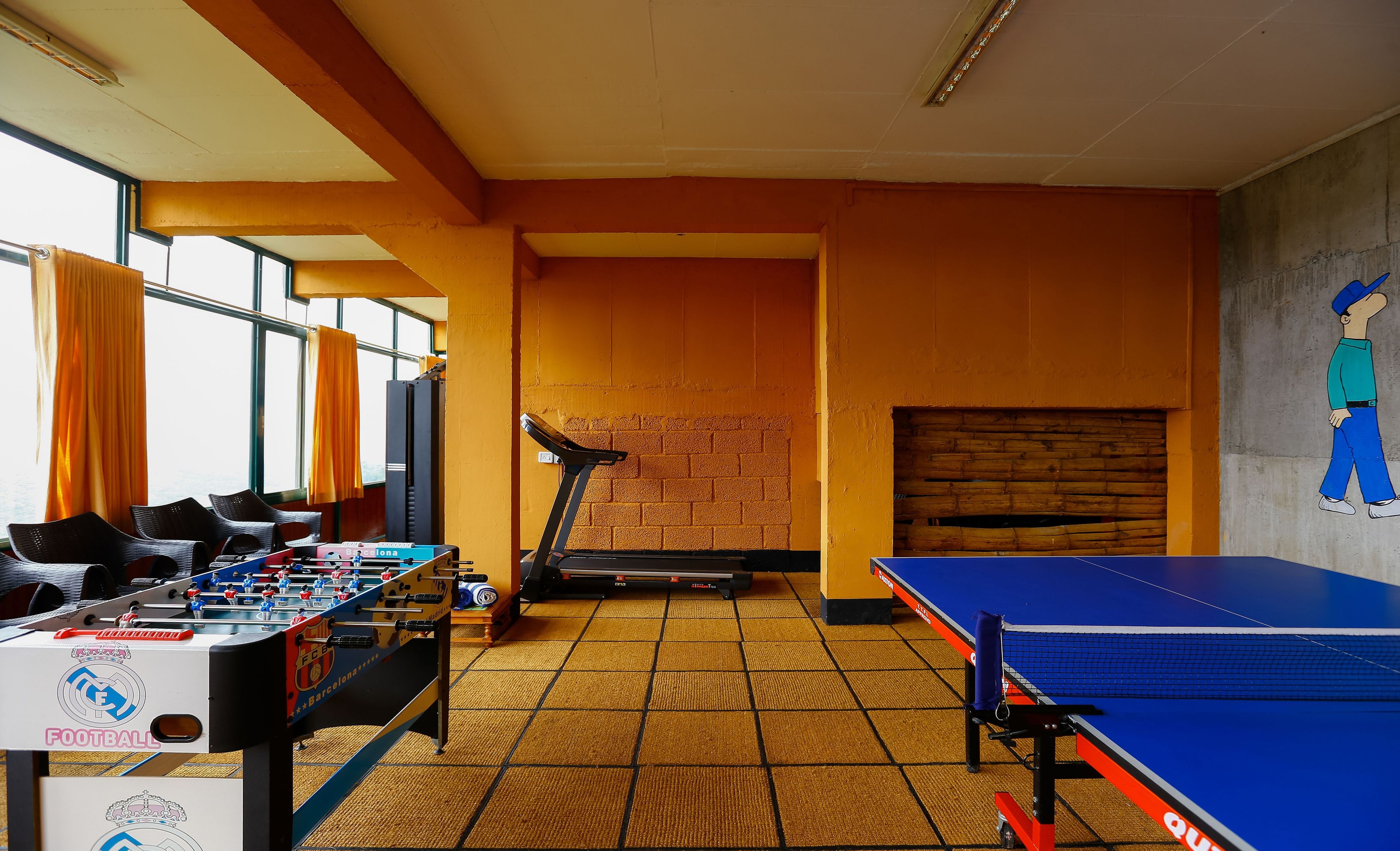 Una habitación con mesa de futbolín, mesa de ping pong y cinta de correr.