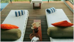 A balcony with two single beds, a small table, and a view of a mountainous landscape. - Spice Tree Munnar (Udumbanchola)