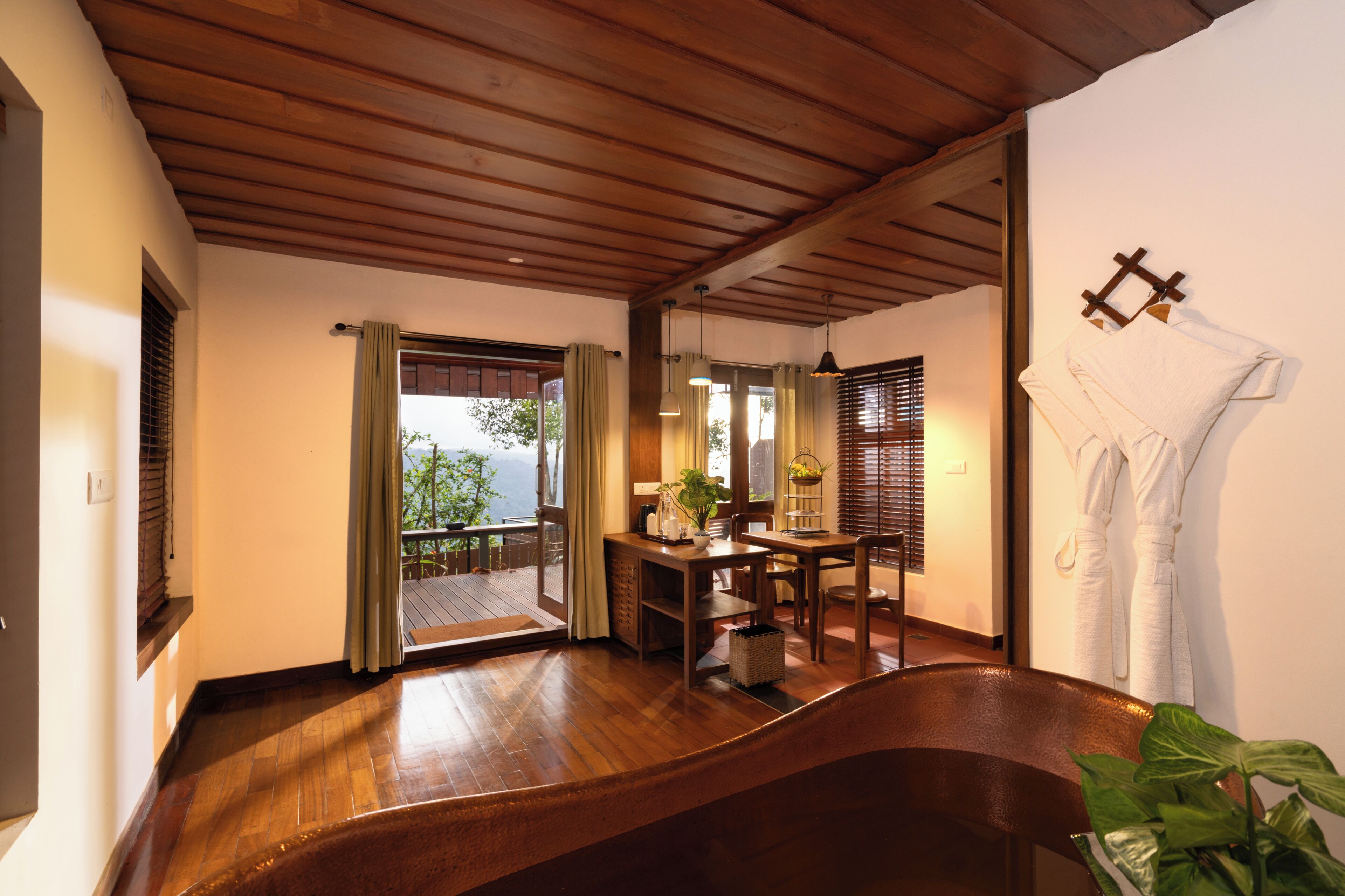 A wooden-floored room with a dining area, a sliding door to a balcony, and a hanging towel rack.