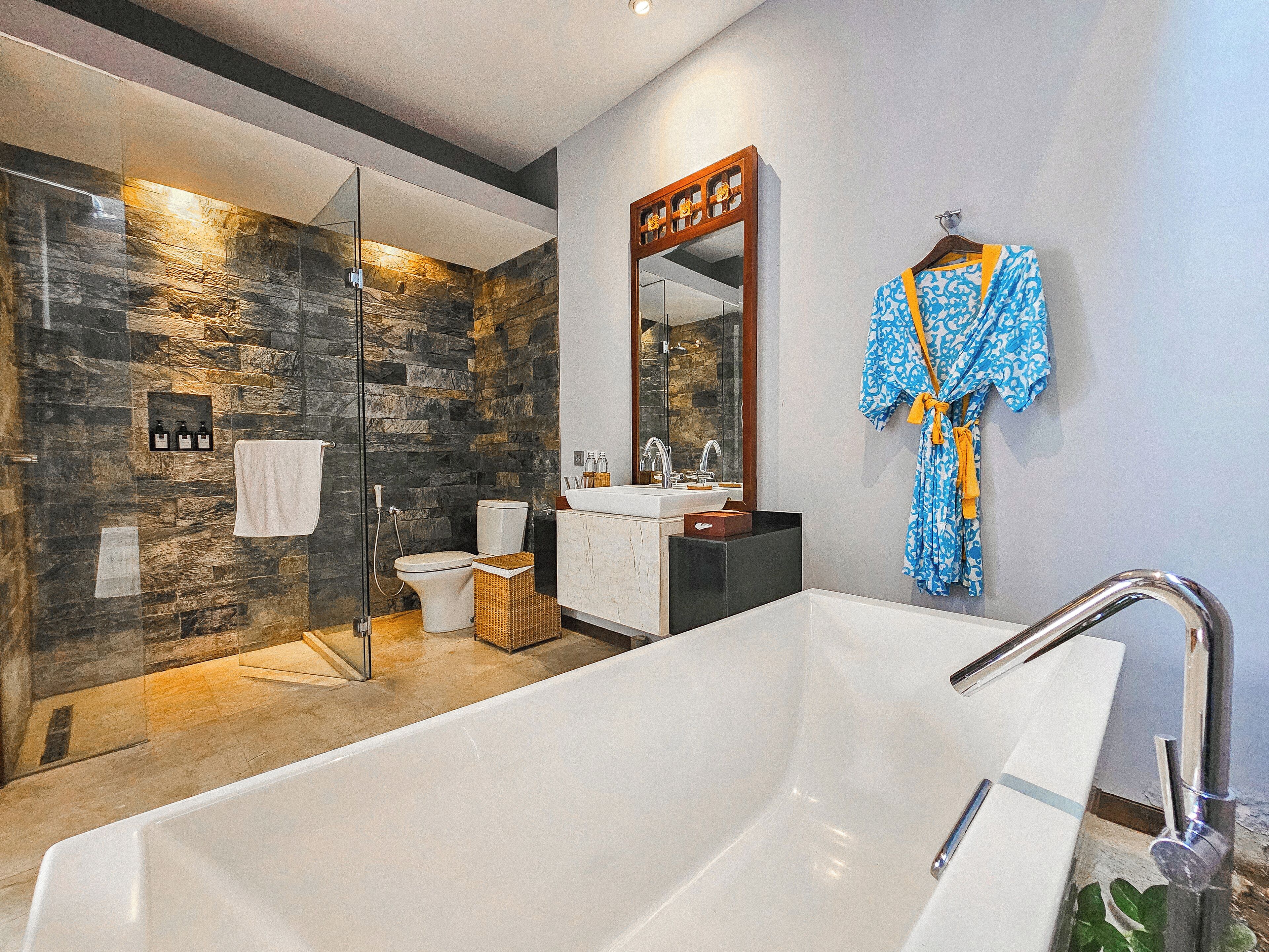 A modern bathroom with a large bathtub, a glass-enclosed shower, and a vanity with a mirror.