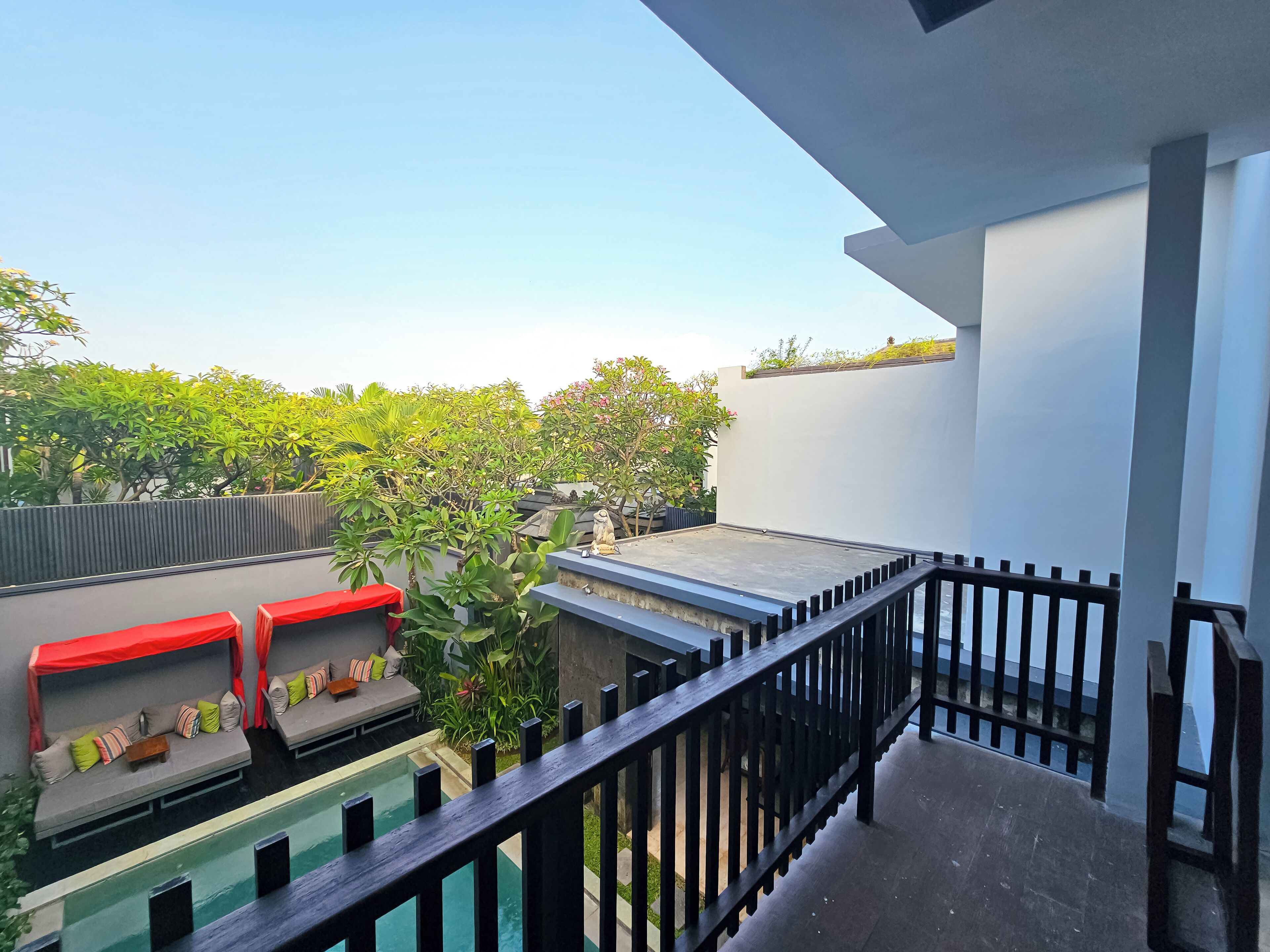A rooftop terrace with a pool, seating area, and a view of greenery.
