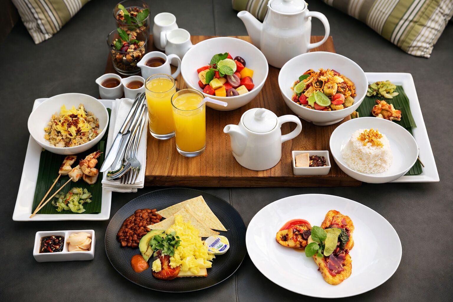 A breakfast buffet with various dishes, including fruit, eggs, and rice.