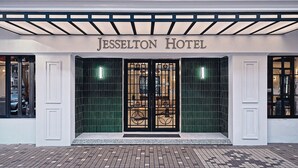 La entrada del Hotel Jesselton, con una fachada clásica, grandes puertas de vidrio y un primer piso con piso de baldosas.