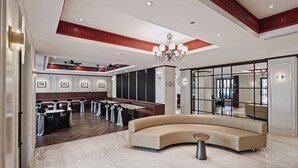 Un vestíbulo amplio con un sofá curvo, un candelabro y una zona de estar con mesas y sillas.
