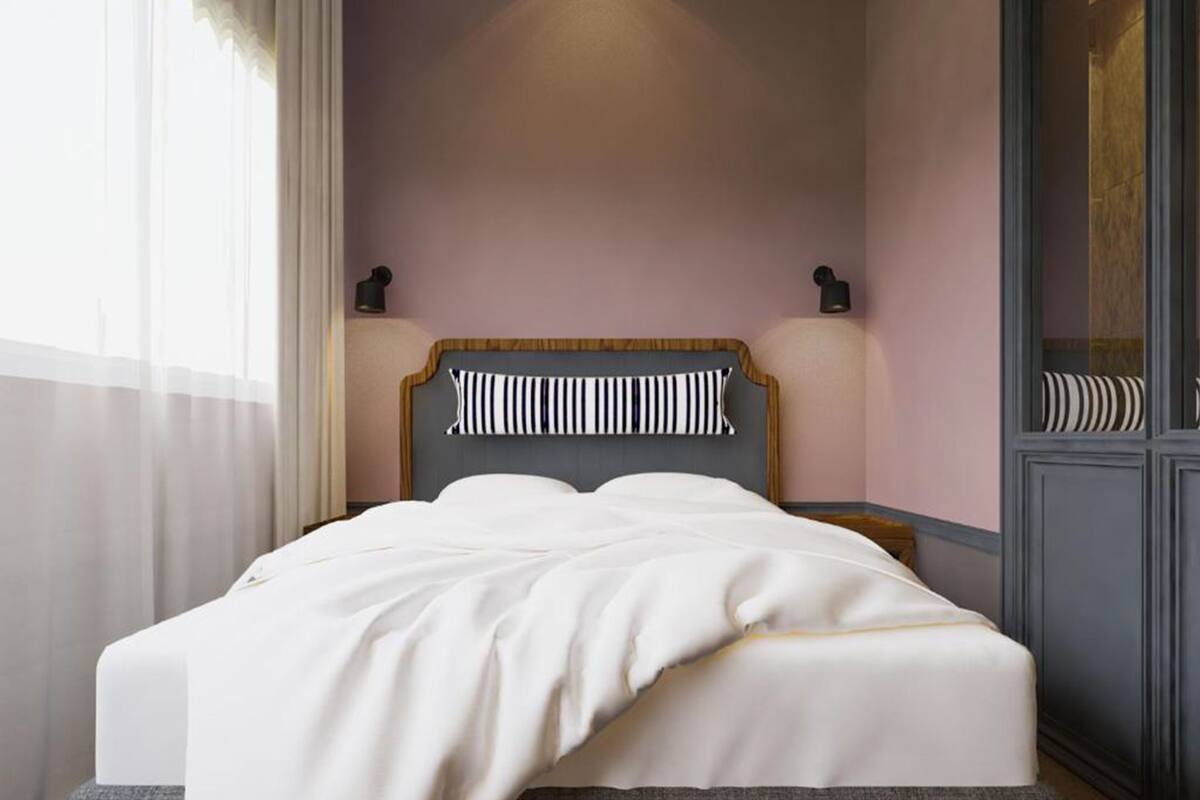 Un lit bien fait, avec un oreiller à rayures, une table de chevet avec une lampe et une armoire avec un miroir.