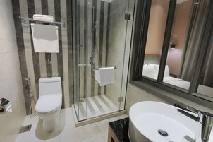 Une salle de bain moderne dotée d’une douche à parois de verre, de toilettes et d’un lavabo avec un plan de travail en marbre.