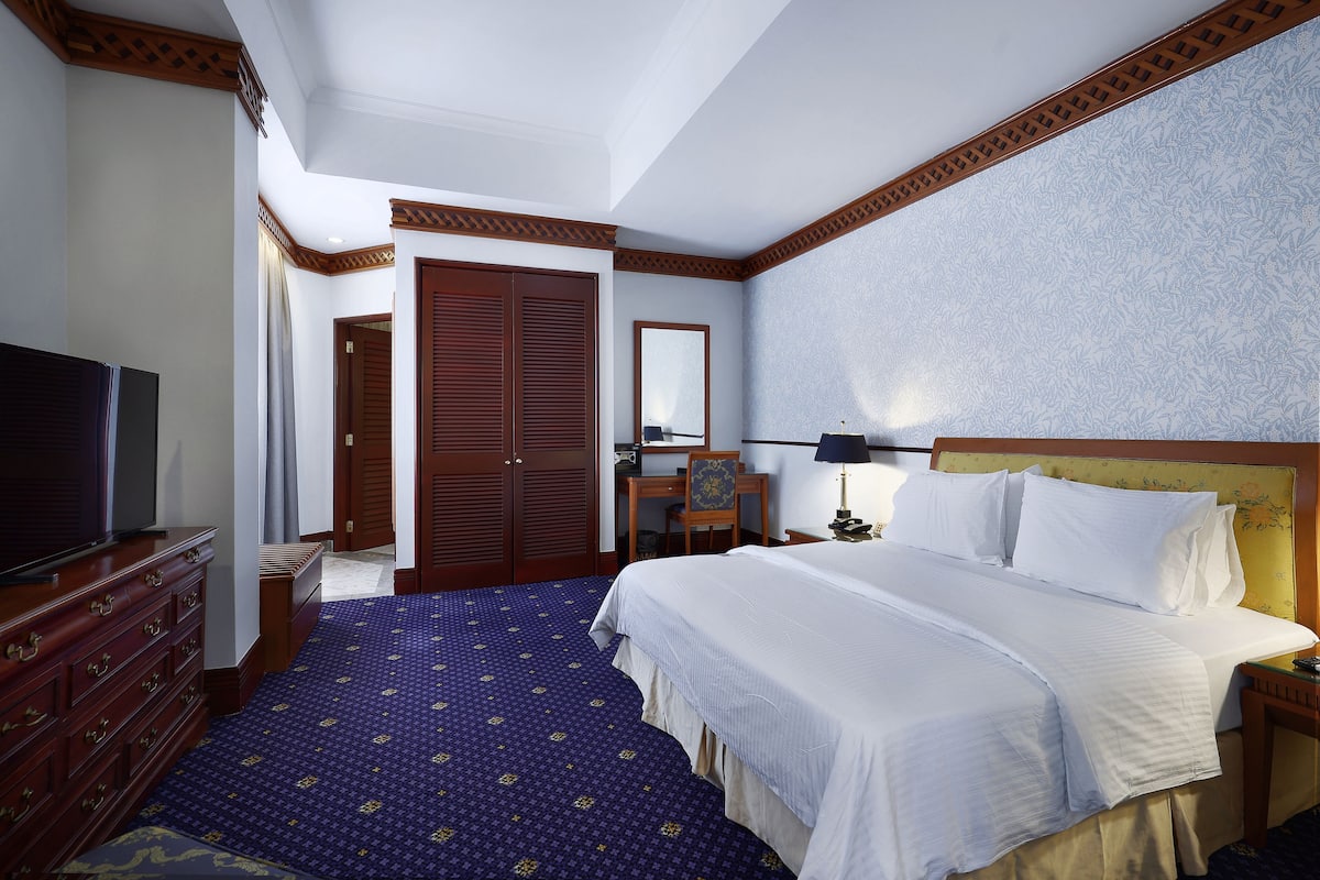 Une chambre d’hôtel avec un grand lit, une télévision, un bureau et une armoire.