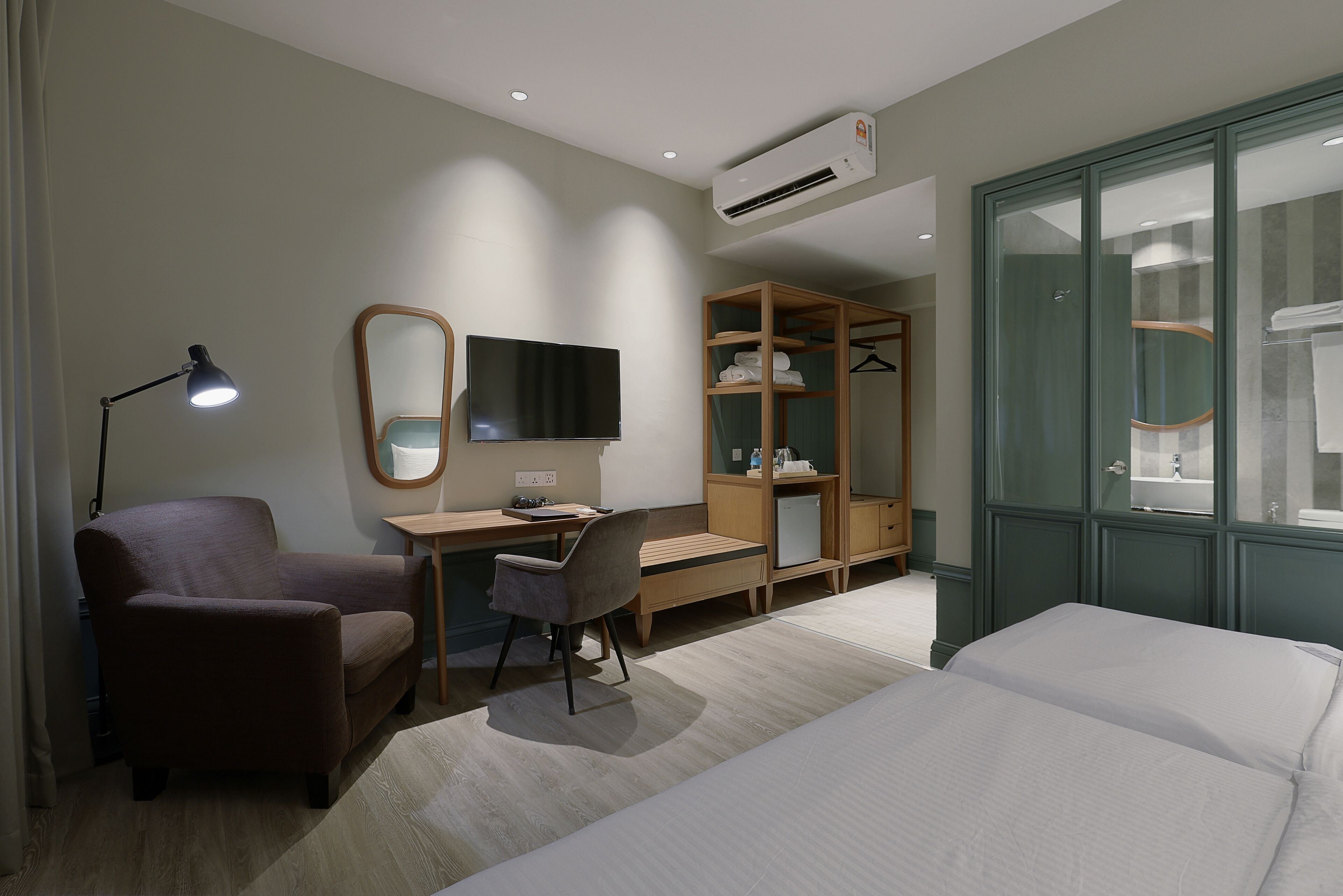 Een hotelkamer met een bed, bureau, stoel, kast, spiegel, televisie en een airconditioner.