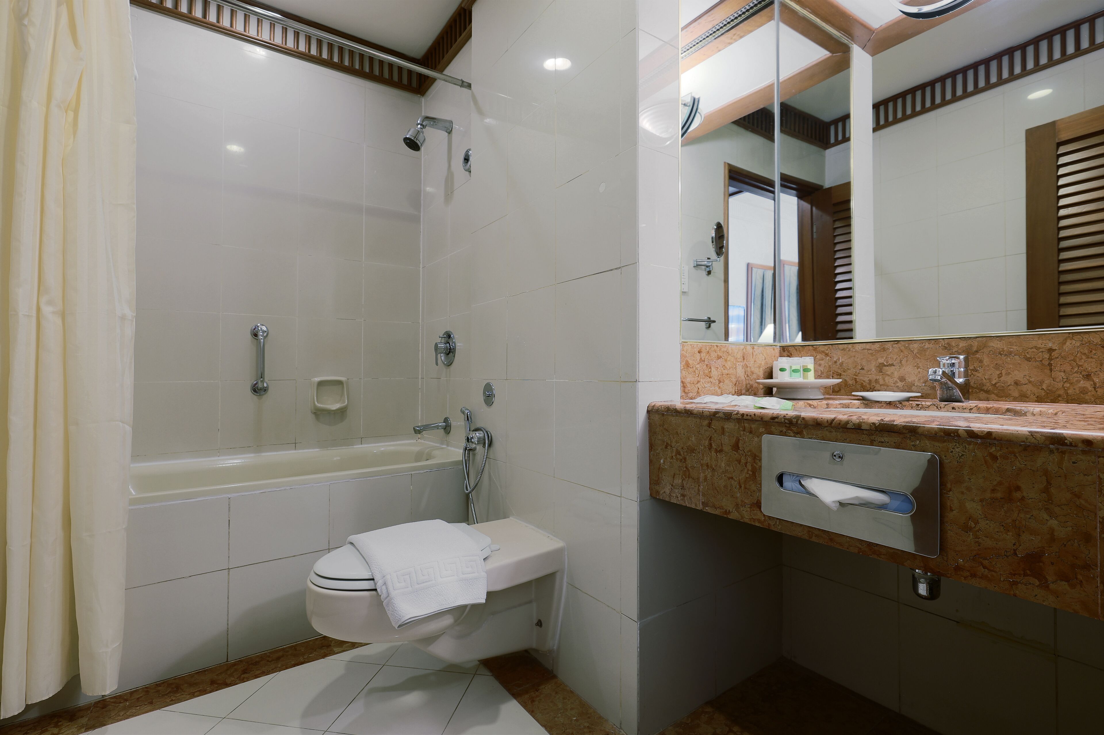 A modern bathroom with a bathtub, shower, toilet, and vanity with a mirror.