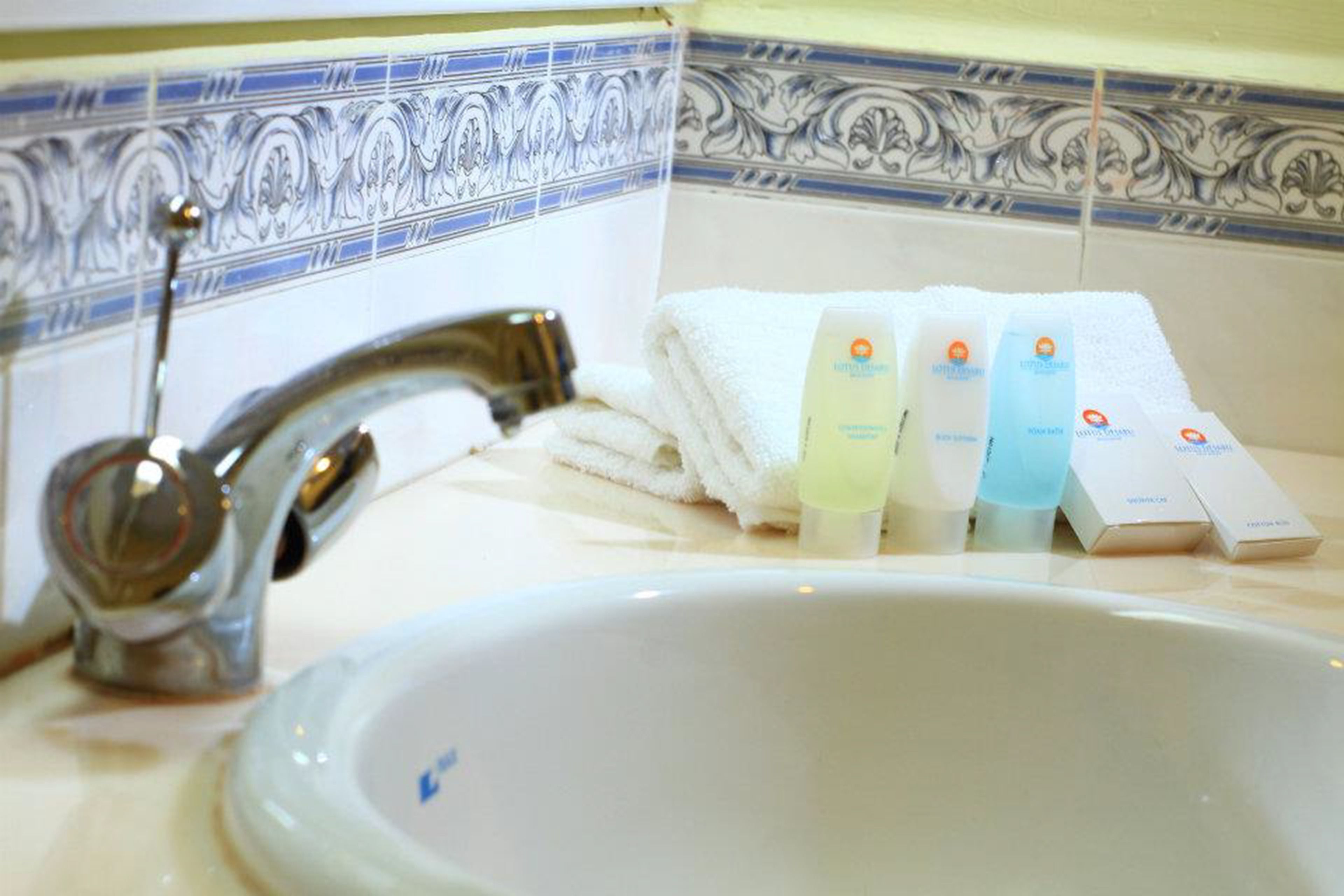 A bathroom sink with a faucet, a towel, and four bottles of lotion.