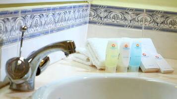 A bathroom sink with a faucet, a towel, and four bottles of lotion.