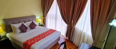A hotel room with a bed, a desk, a chair, and a window with curtains.