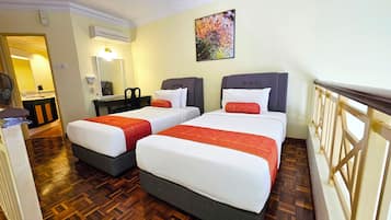Habitación de hotel con dos camas, un escritorio, una silla, un espejo y un cuadro en la pared.
