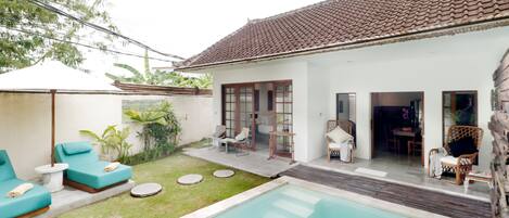 Ein Poolbereich mit Schwimmbecken, Liegestühlen und einer Terrasse mit Tisch und Stühlen.