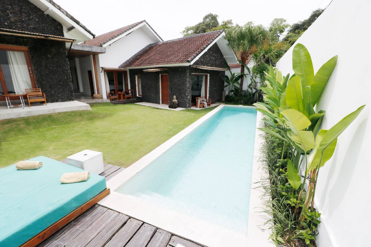A swimming pool with a wooden deck, a lounge chair, and a small table.