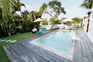 Una piscina al aire libre, sombrillas, sillones reclinables de piscina