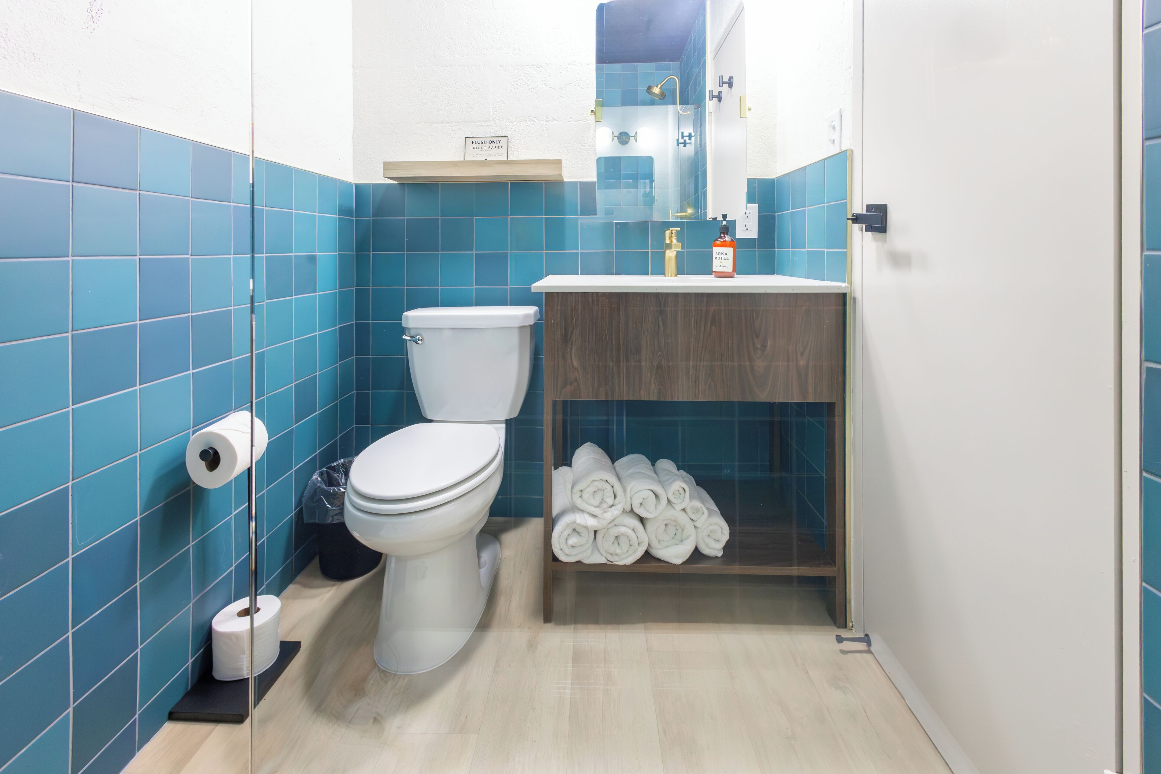 Une salle de bain comprenant des toilettes, un lavabo et une étagère avec des serviettes pliées.