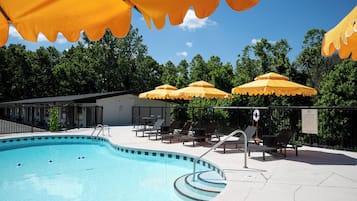 A swimming pool with sun umbrellas, lounge chairs, and a lifebuoy.