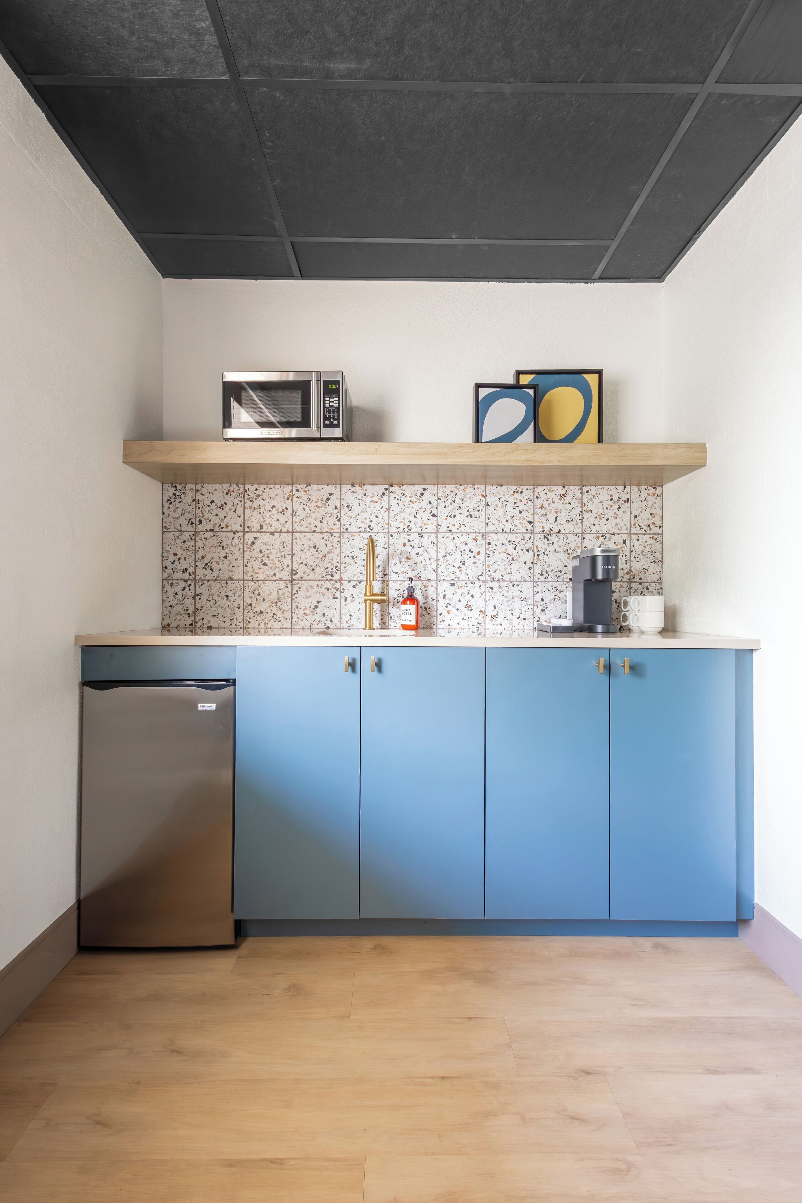 A compact kitchen with a microwave, coffee maker, and a small refrigerator.