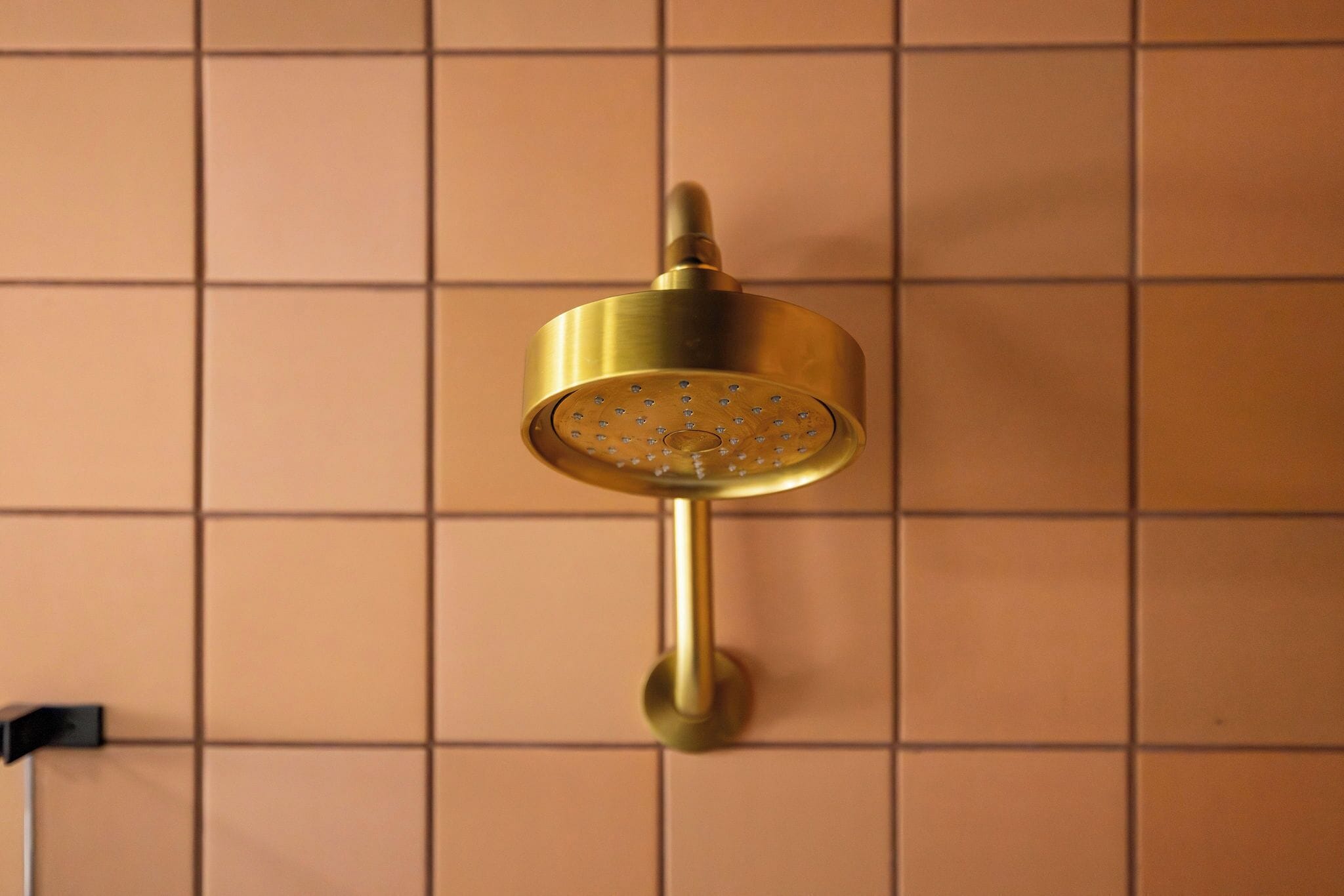Une pomme de douche murale au design cylindrique, dotée d’une seule poignée.