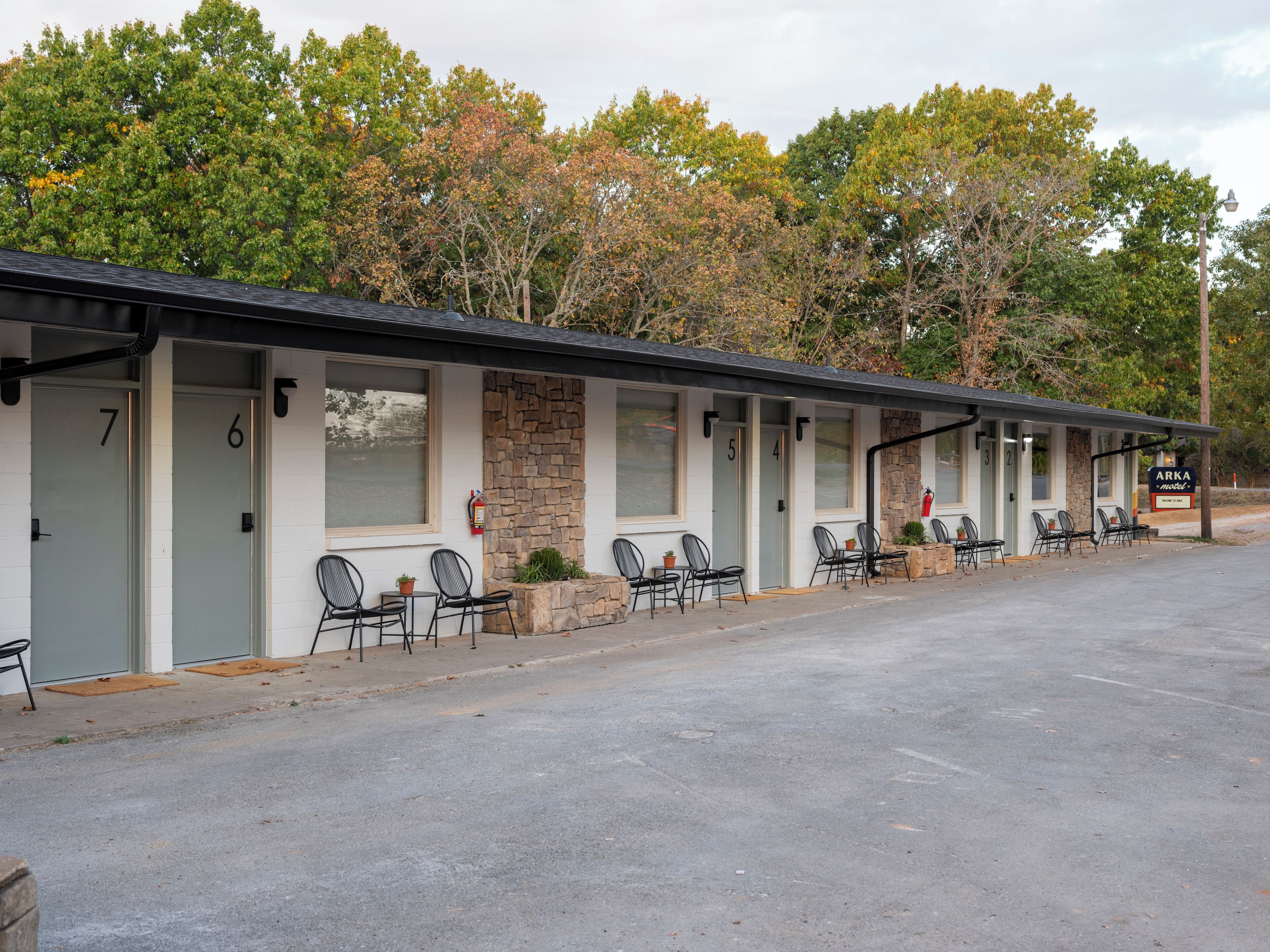 Un motel avec des chambres numérotées, des places assises à l’extérieur et une enseigne indiquant « ARKA Motel ».