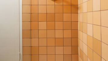 A shower with a gold showerhead and a gold control panel.