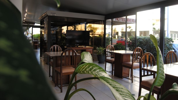 A restaurant with wooden tables and chairs, a television, and potted plants. - Hotel 24 (Punta del Este)