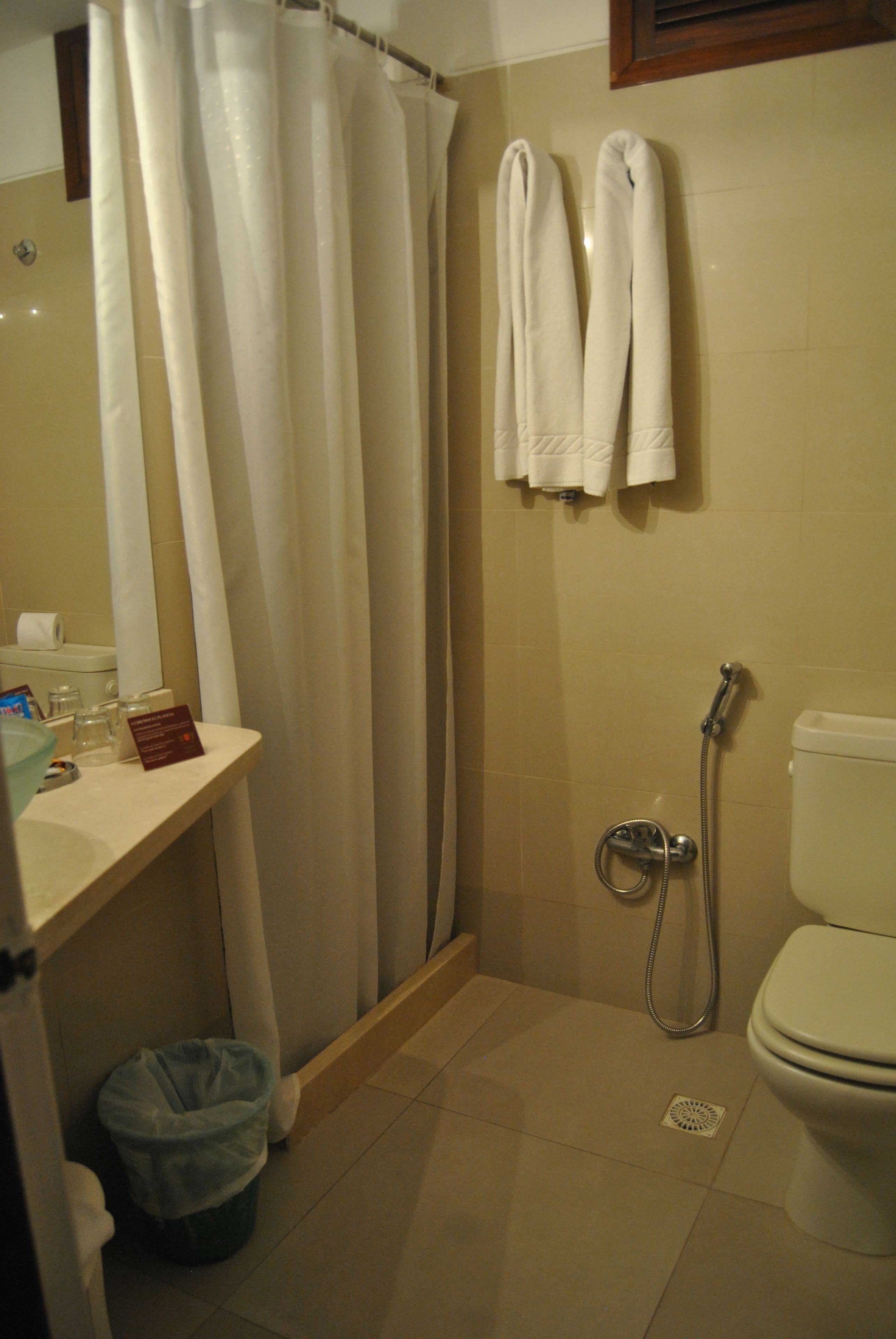 Un baño con ducha, inodoro y lavamanos con artículos de aseo.