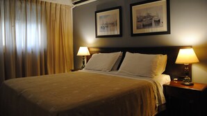 A hotel room with a large bed, two bedside lamps, a framed picture on the wall, and a window with curtains. - Hotel 24 (Punta del Este)