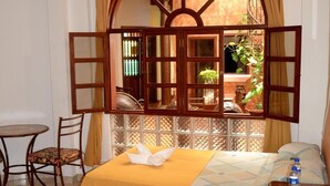 A room with a bed, a chair, a small table, and a window with curtains. - Hotel Villa Florencia Centro (San Salvador)