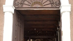 An ornate wrought iron gate with a decorative archway, leading to a building entrance. - Hotel Villa Florencia Centro (San Salvador)