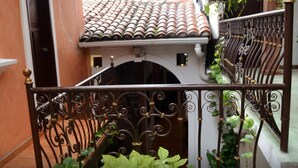 A staircase with ornate iron railings, a tiled roof, and potted plants. - Hotel Villa Florencia Centro (San Salvador)