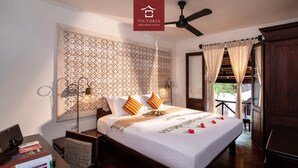A neatly arranged bedroom with a bed, bedside tables, a desk, and a chair. - Victoria Xiengthong Palace (Luang Prabang)