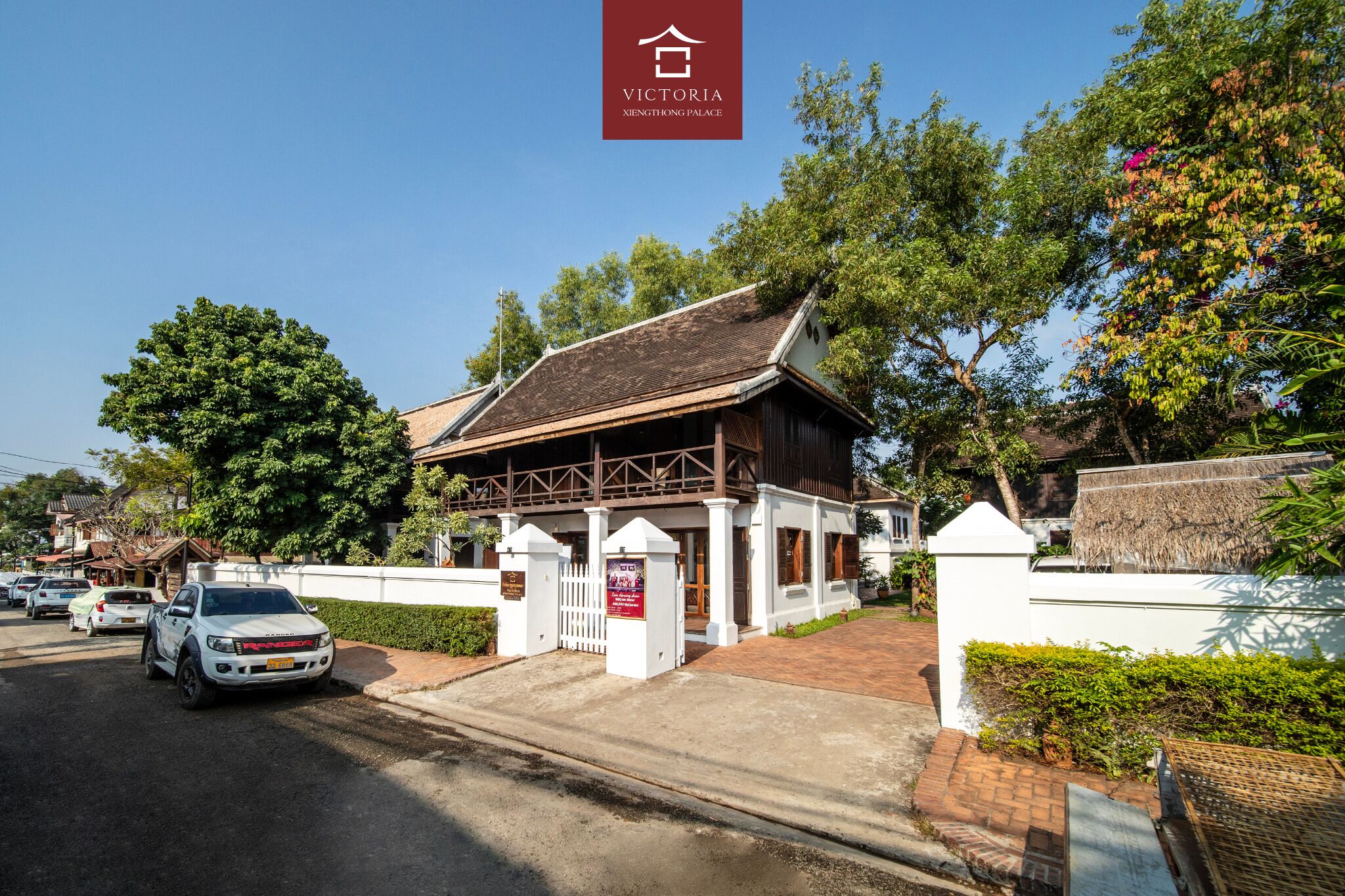 A traditional building with a thatched roof, a white fence, and a sign indicating it is Victoria Xietong Palace.