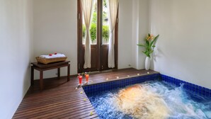 A spa room with a wooden floor, a hot tub, a small table with a basket and towels, and a potted plant. - Victoria Xiengthong Palace (Luang Prabang)