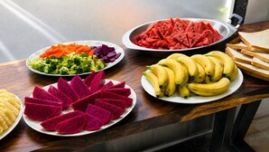 Uma mesa com diversas frutas e legumes, incluindo pitaya, melancia e bananas.