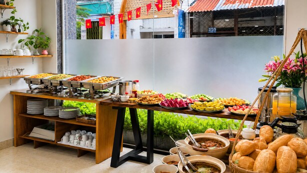 Buffet com diversas opções de comida, um espaço para café e vista para a rua.