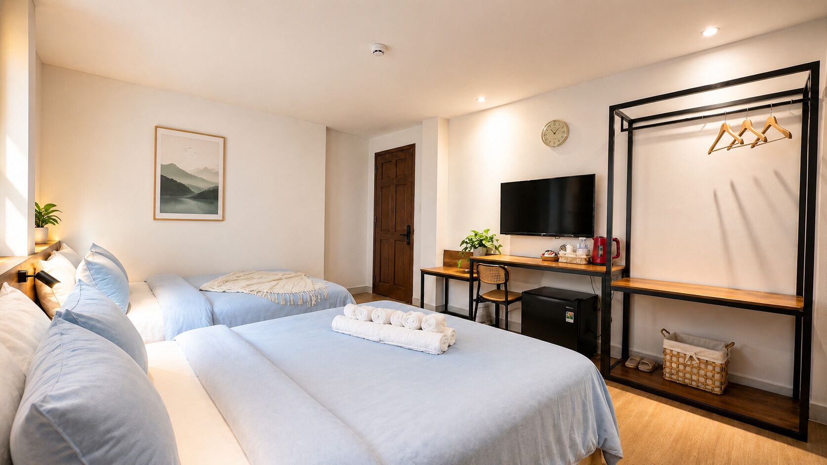 Habitación de hotel con dos camas, un escritorio, un televisor, un armario y una planta.