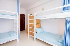 Een kamer met stapelbedden, genummerd 301-A en 301-B, een houten trapje en een klok aan de muur.