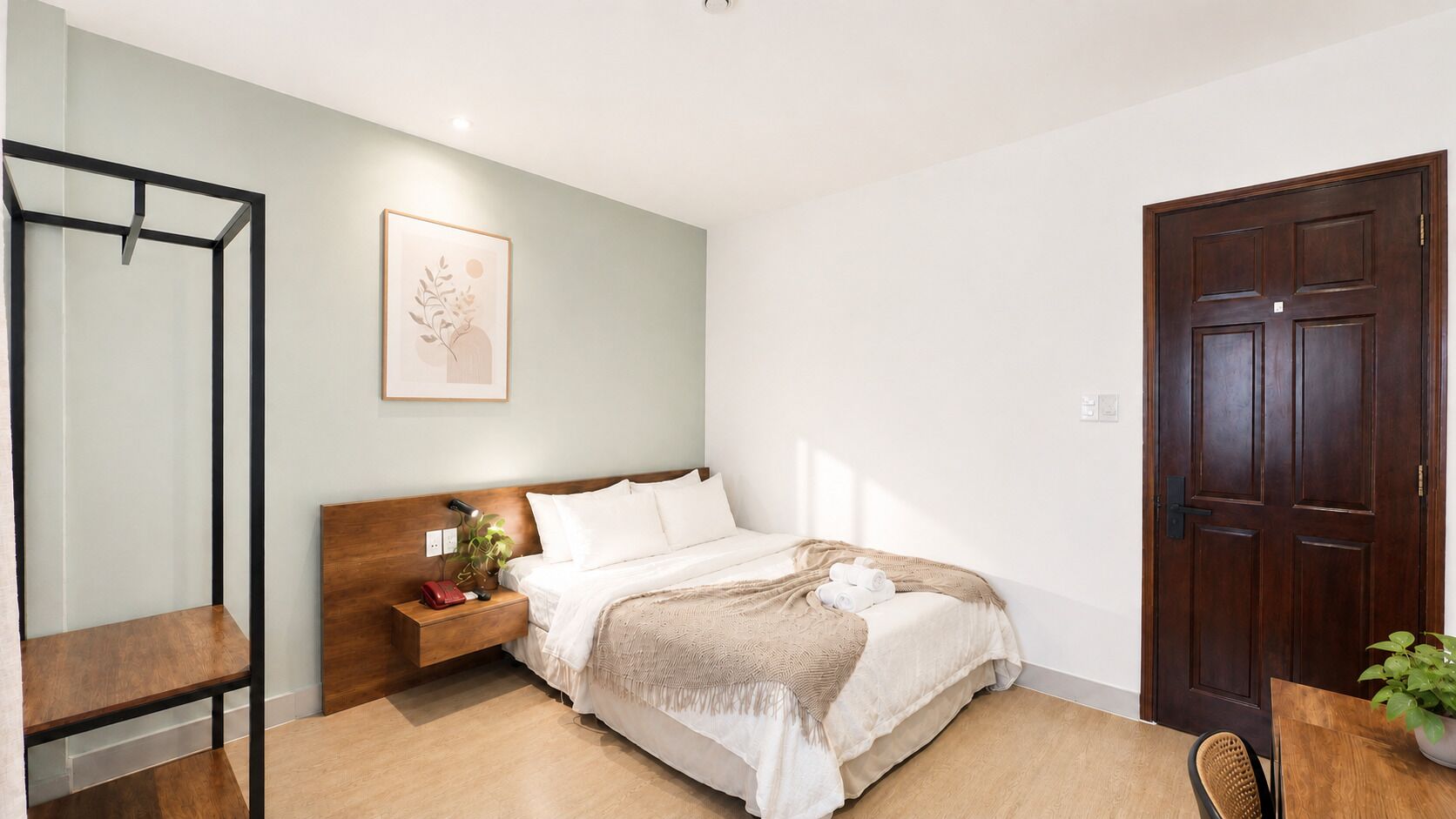 A bedroom with a bed, bedside table, nightstand, and a door.