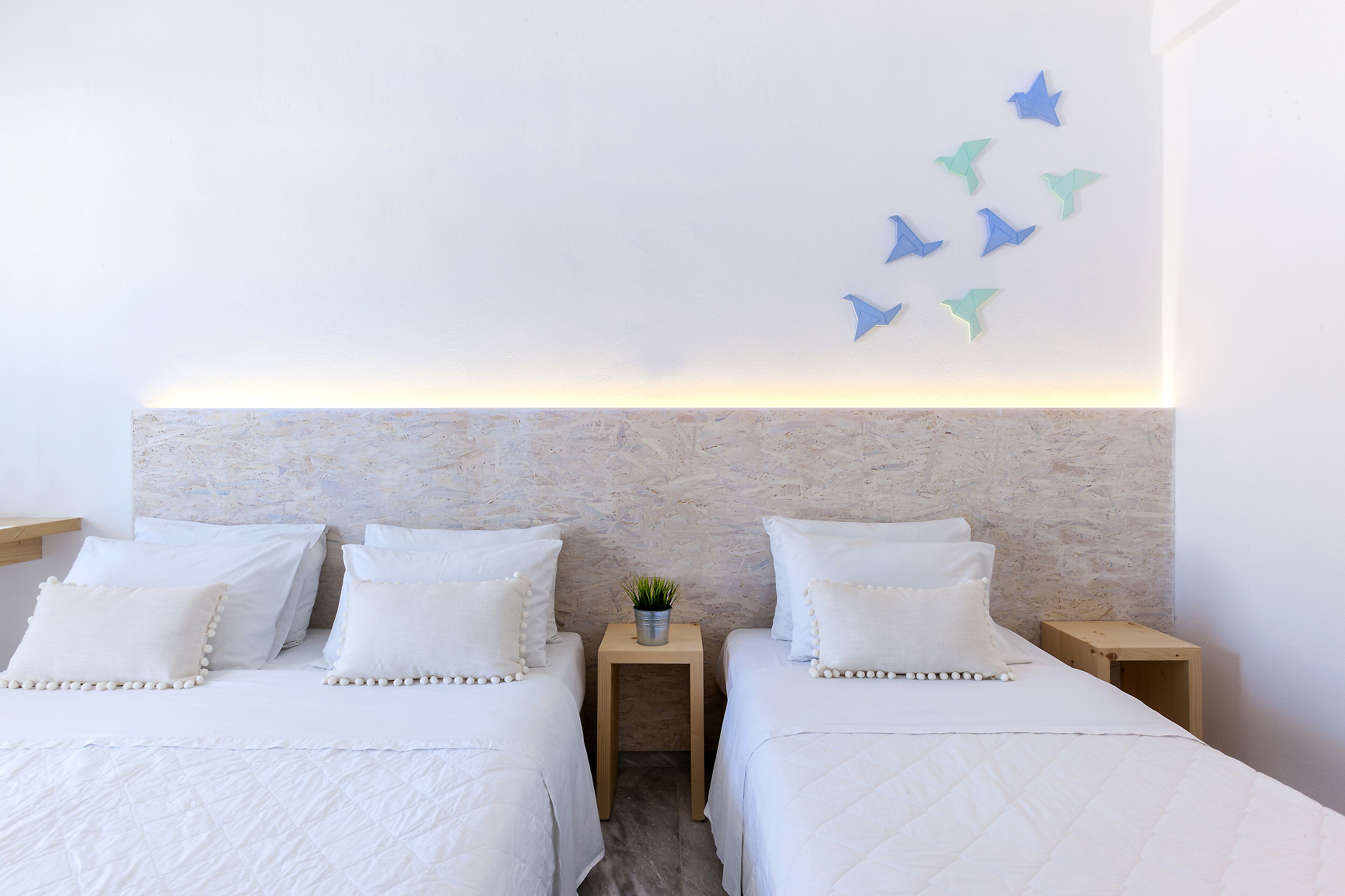 Quarto de hotel com duas camas, cabeceira de mármore, uma pequena planta em uma mesa de cabeceira e parede decorada com estrelas.