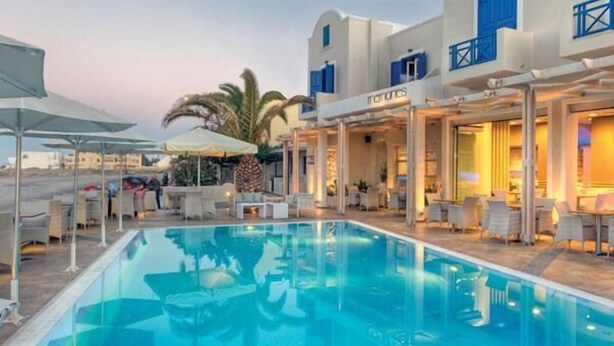 Zona de piscina con sillones de playa y sombrillas, una piscina y un edificio con fachada azul y un letrero que dice "Marmaris".