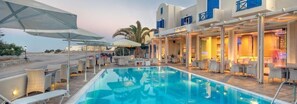 A poolside area with lounge chairs and umbrellas, a pool, and a building with a blue facade and a sign that reads "Marmaris."