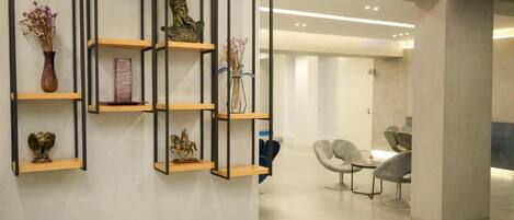 A modern interior with wooden shelves displaying decorative items, a seating area with chairs, and a clean, minimalist design.