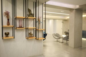Un interno moderno con mensole in legno che espongono oggetti decorativi, un'area salotto con poltrone e un design pulito e minimalista.