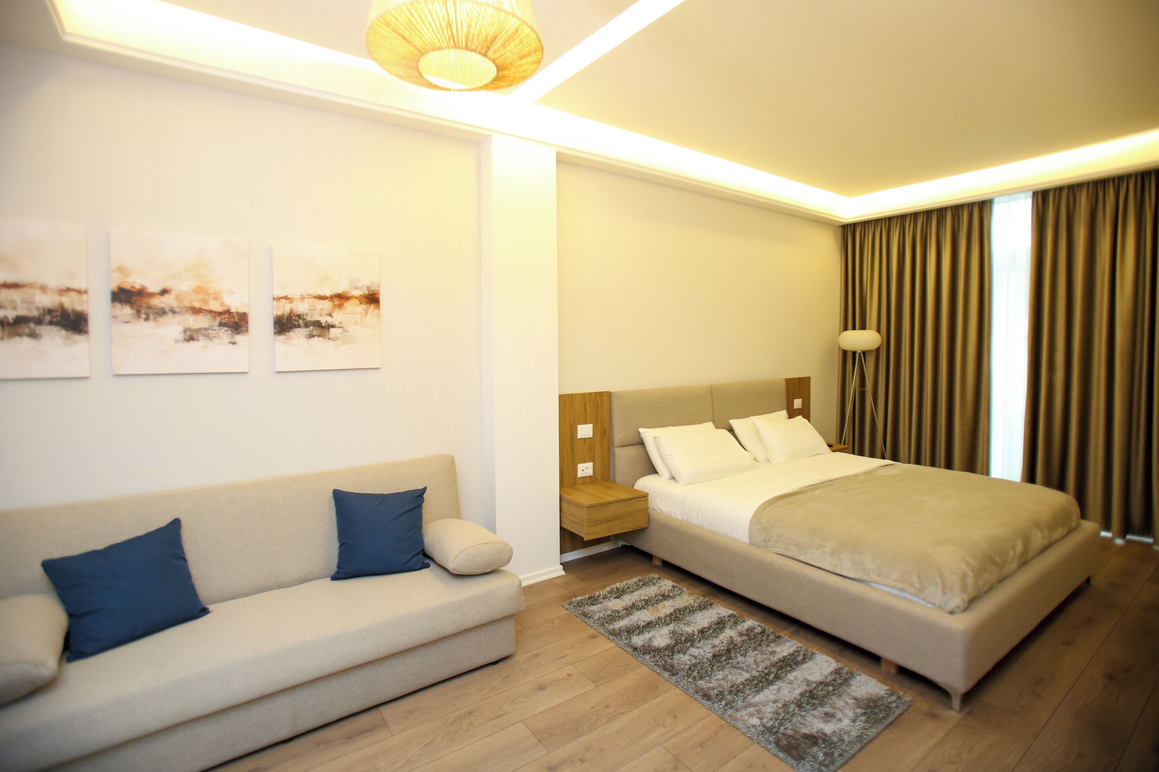 Een moderne hotelkamer met een bank, een bed, een nachtkastje en kunst aan de muur.