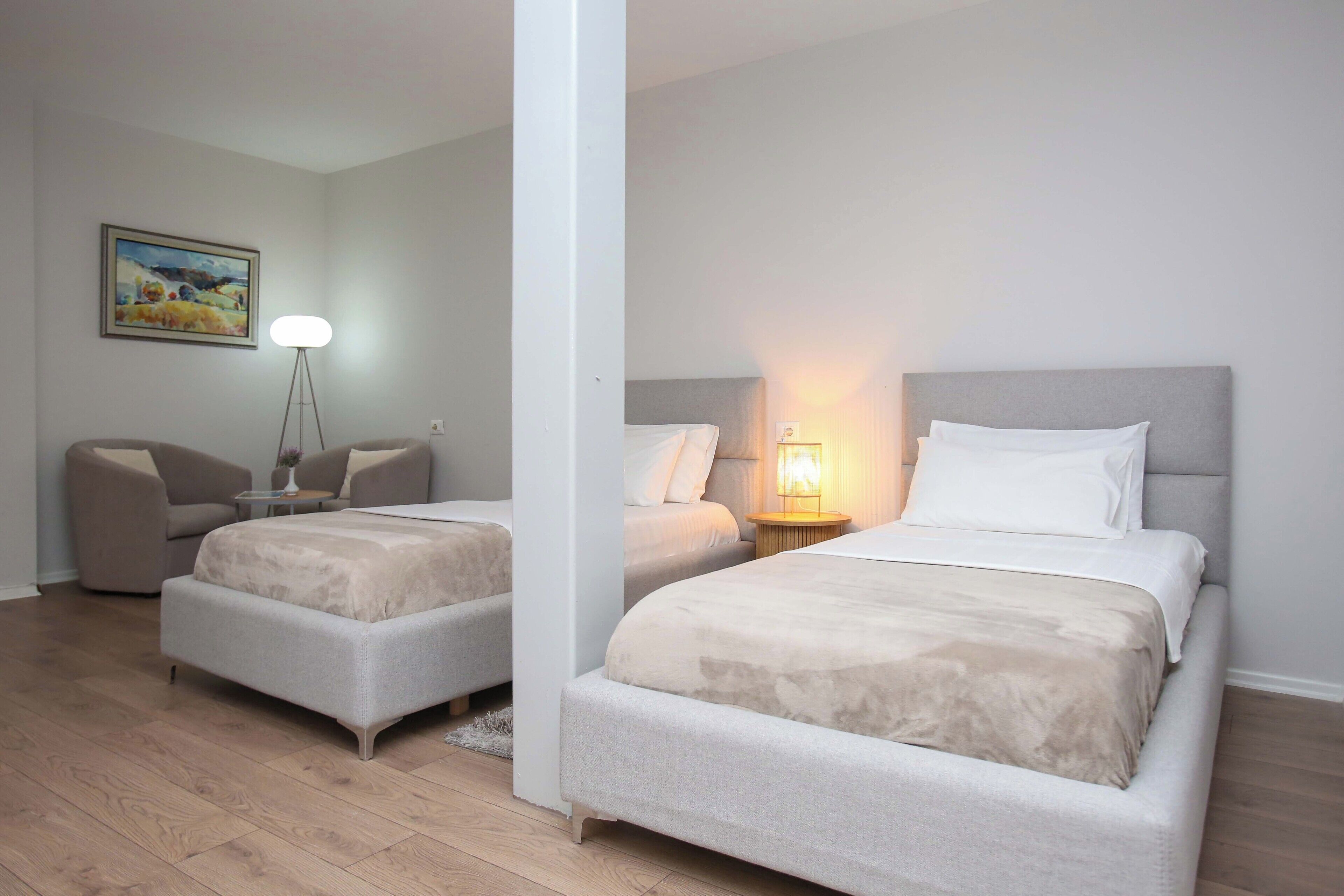 Una habitación de hotel con dos camas, un sofá, una lámpara y un cuadro en la pared.