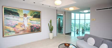A modern interior with a large floral painting, a grey sofa, a small table, and a potted plant.