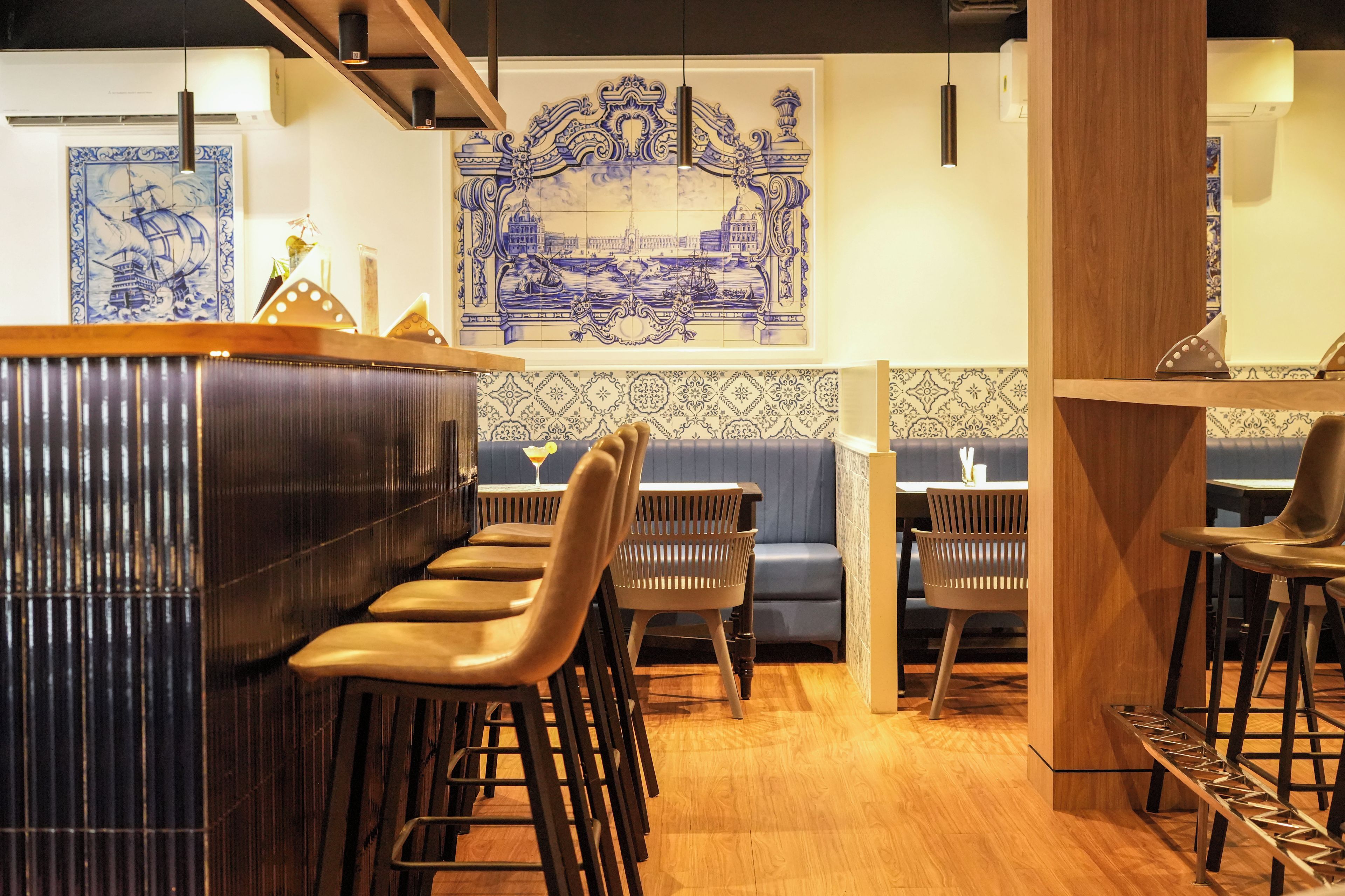 A bar area with stools, a wooden counter, and a patterned wall behind the bar.